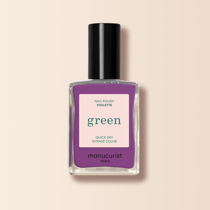 A bottle of Manucurist nail polish in the Violette retro purple shade, featuring a black cap and beige label with green and purple text.