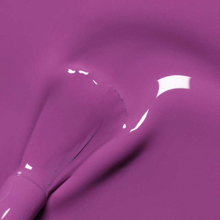 A close-up of a brush applying Violette nail polish from Manucurist, creating smooth, glossy streaks and vibrant reflections on the surface.