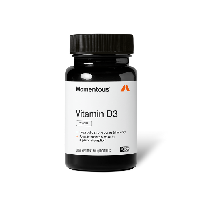 Product photo of a black Momentous Vitamin D3 bottle on a plain black background. Label text: "Momentous" (with triangle logo) / "Vitamin D3" / "2000IU" / "Helps build strong bones & immunity†" / "Formulated with olive oil for superior absorption†" / "DIETARY SUPPLEMENT 60 LIQUID CAPSULES" with NSF Certified Sport badge.