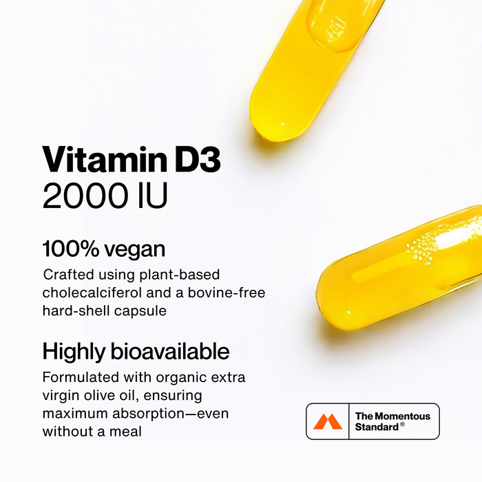 White background with two golden softgel capsules in opposite corners. Text: "Vitamin D3 2000 IU" / "100% vegan" / "Crafted using plant-based cholecalciferol and a bovine-free hard-shell capsule" / "Highly bioavailable" / "Formulated with organic extra virgin olive oil, ensuring maximum absorption—even without a meal." Logo mark and "The Momentous Standard" wordmark in bottom corner.